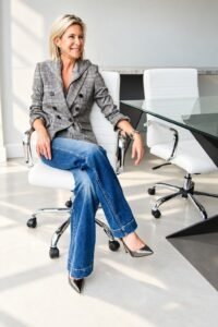 Angela Howenstein wearing a gray plaid double-breasted blazer with jeans and pointed-toe heels.