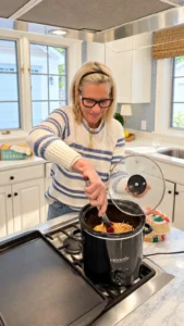 Angela Howenstein wearing a cream and blue striped sweater while cooking in her kitchen.
