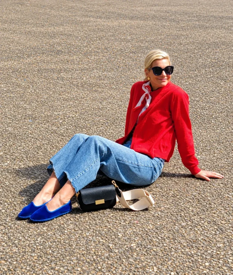 Angela Howenstein wearing blue suede flats with wide-leg jeans, a red cardigan and a neck scarf.