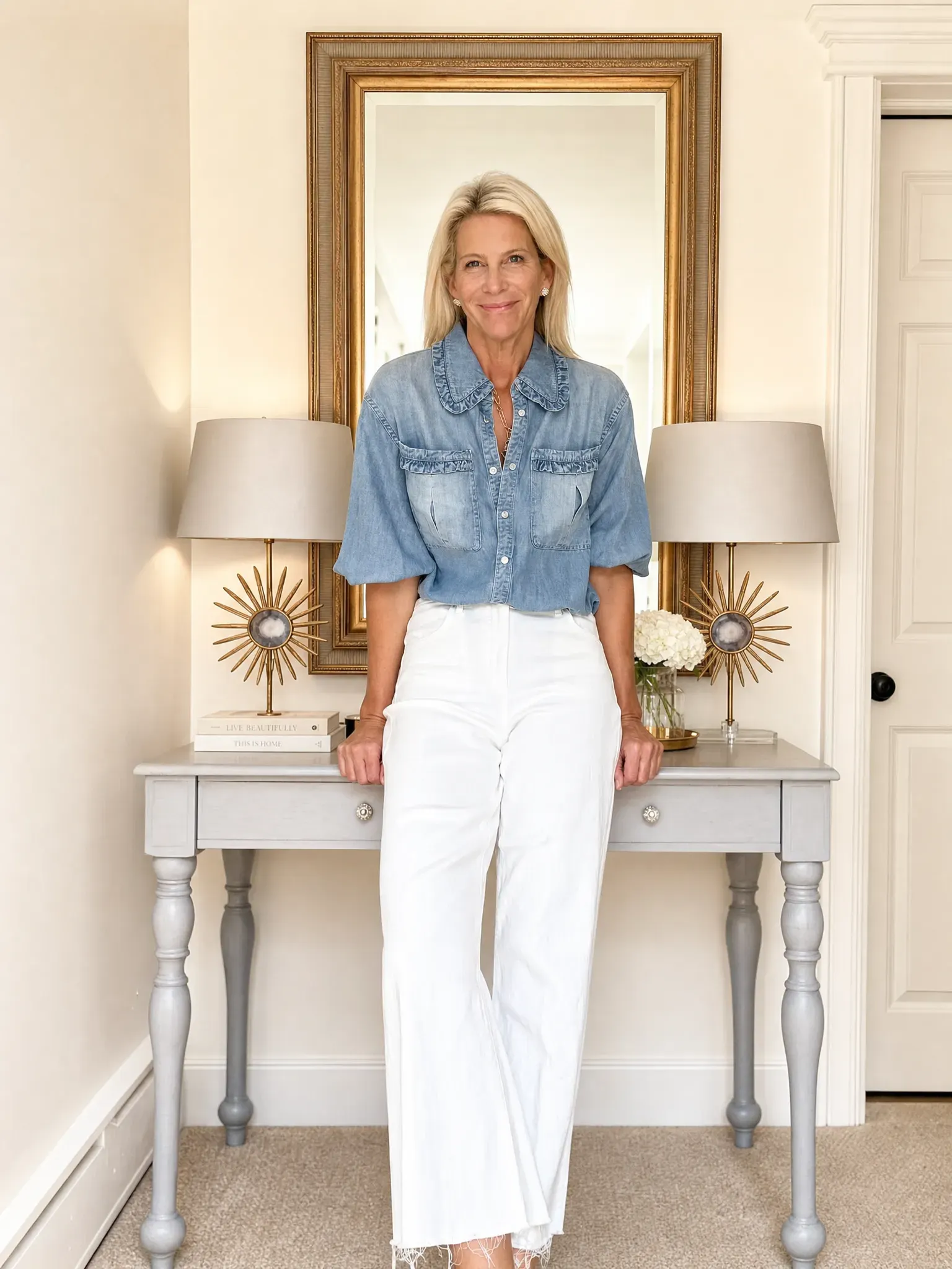 Angela wearing a washed-blue ruffle-trim shirt with white wide-leg trousers.