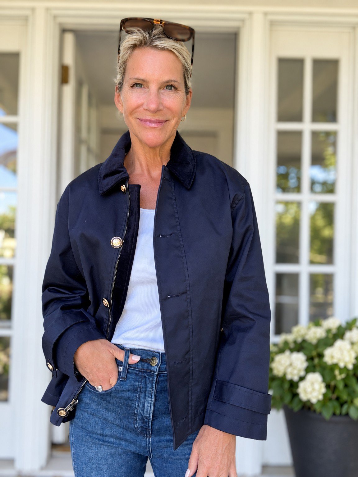 Angela in a navy jacket with gold buttons over a white top and jeans.