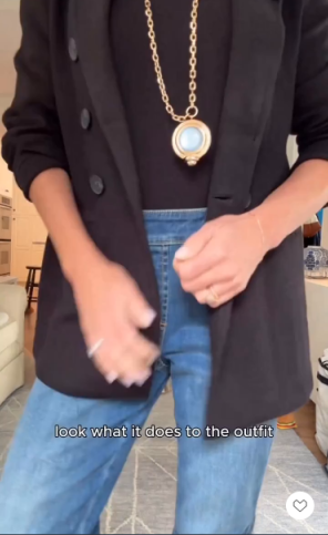 A black blazer and top, blue jeans, and a gold pendant necklace.